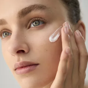 Close up of person applying Comforting Barrier Mask on their face with their hand 
